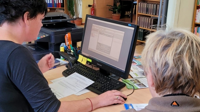 Bibliotekāre datorā aizpilda pabalsta pieteikuma veidlapu apmeklētājai