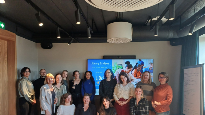 Semināra dalībnieku kopbilde, kur dalībnieki stāv pie ekrāna ar projekta logo