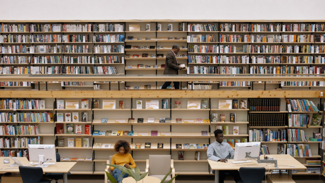 Bibliotēka ar grāmatplauktiem fonā un diviem lasītājiem priekšplānā