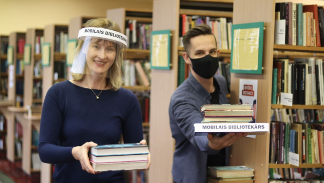 Bibliotekāri ar sejas aizsegiem kārto grāmatas 