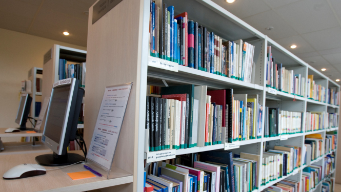 Bibliotēkas grāmatu plaukts ar datoru