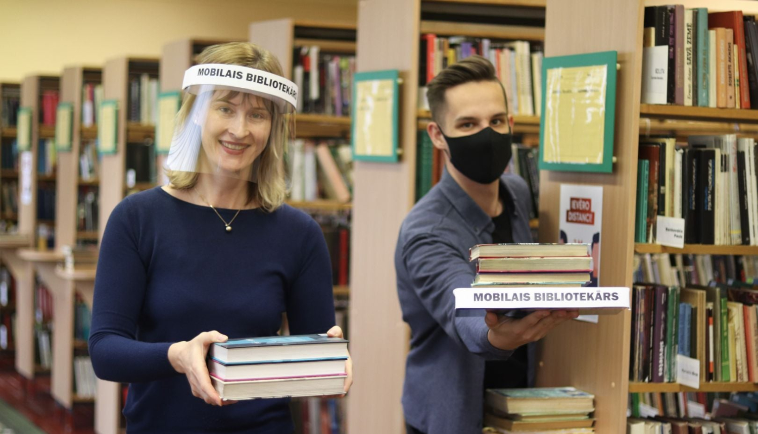 Bibliotekāri ar sejas aizsegiem kārto grāmatas 